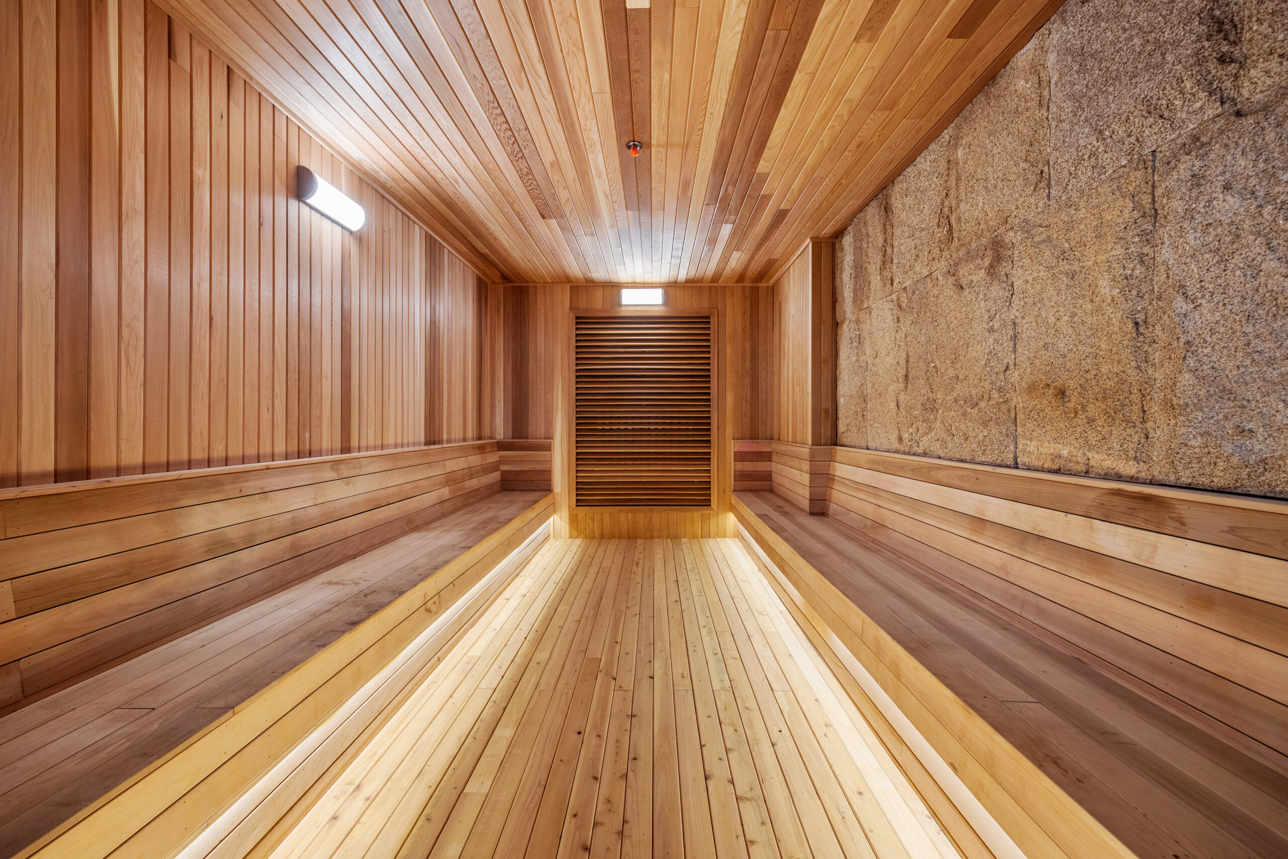 Inside the dry sauna, made of wood with seating area along the length of the room.