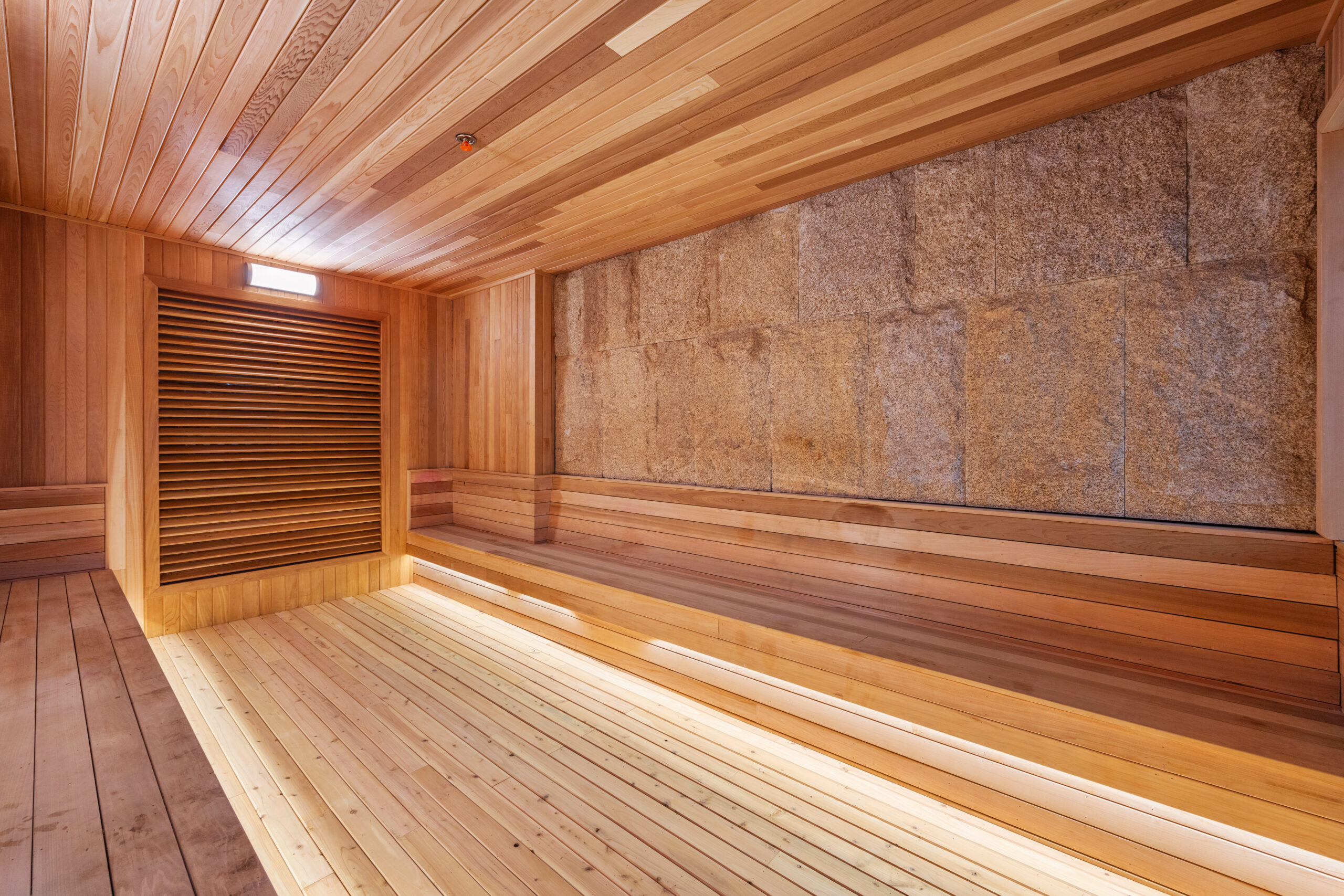 Side angle of the dry sauna, made of wood with seating area along the length of the room.