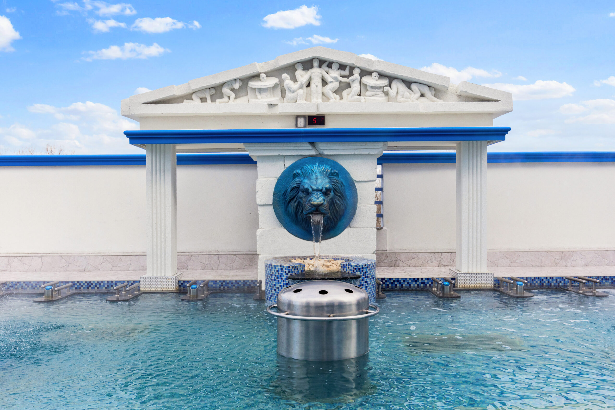 View of lion water fountain located inside the seated outdoor medi pool.