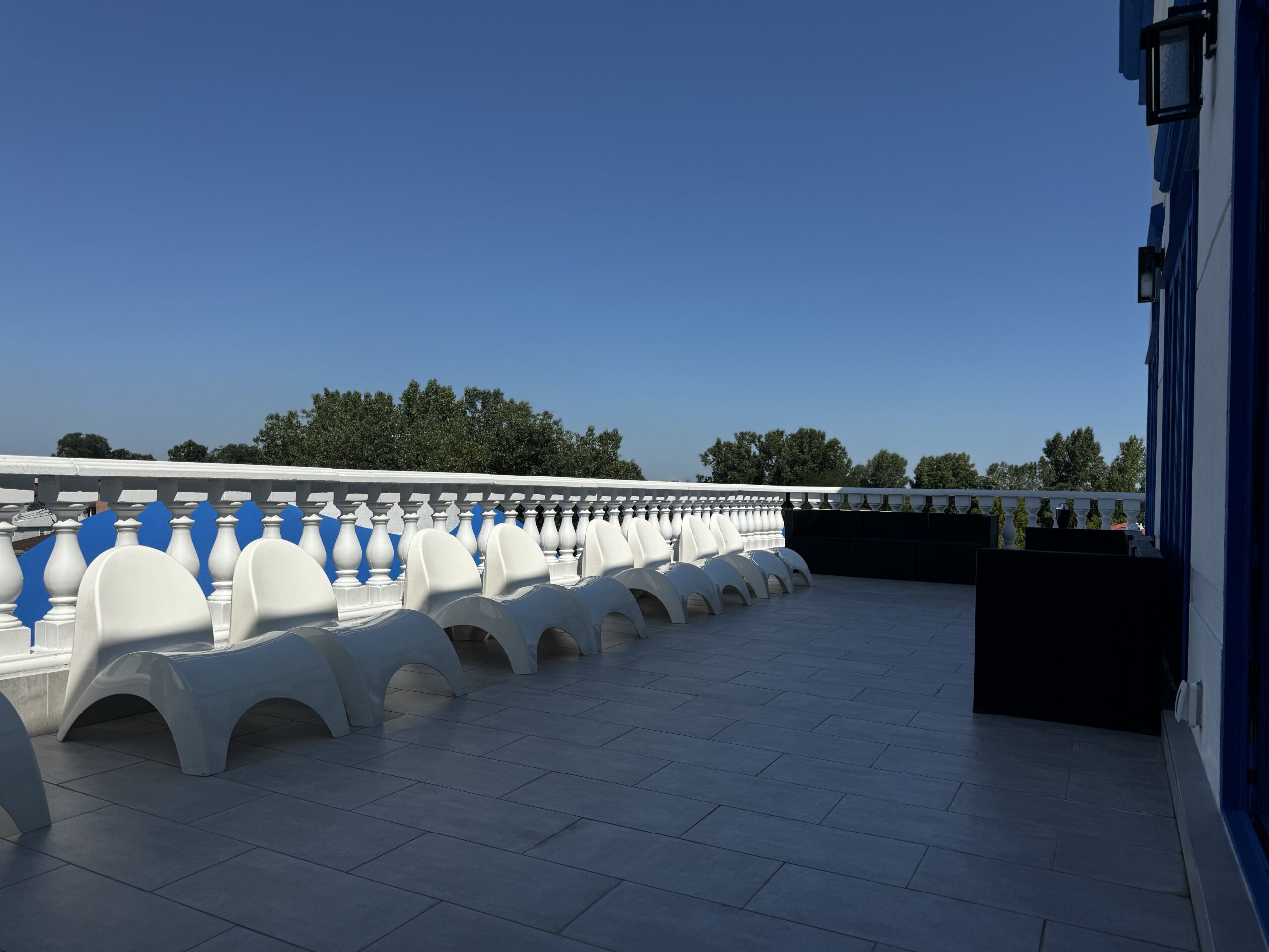 View of the outdoor smoking area, sun deck. featuring white chairs and lounge seating.