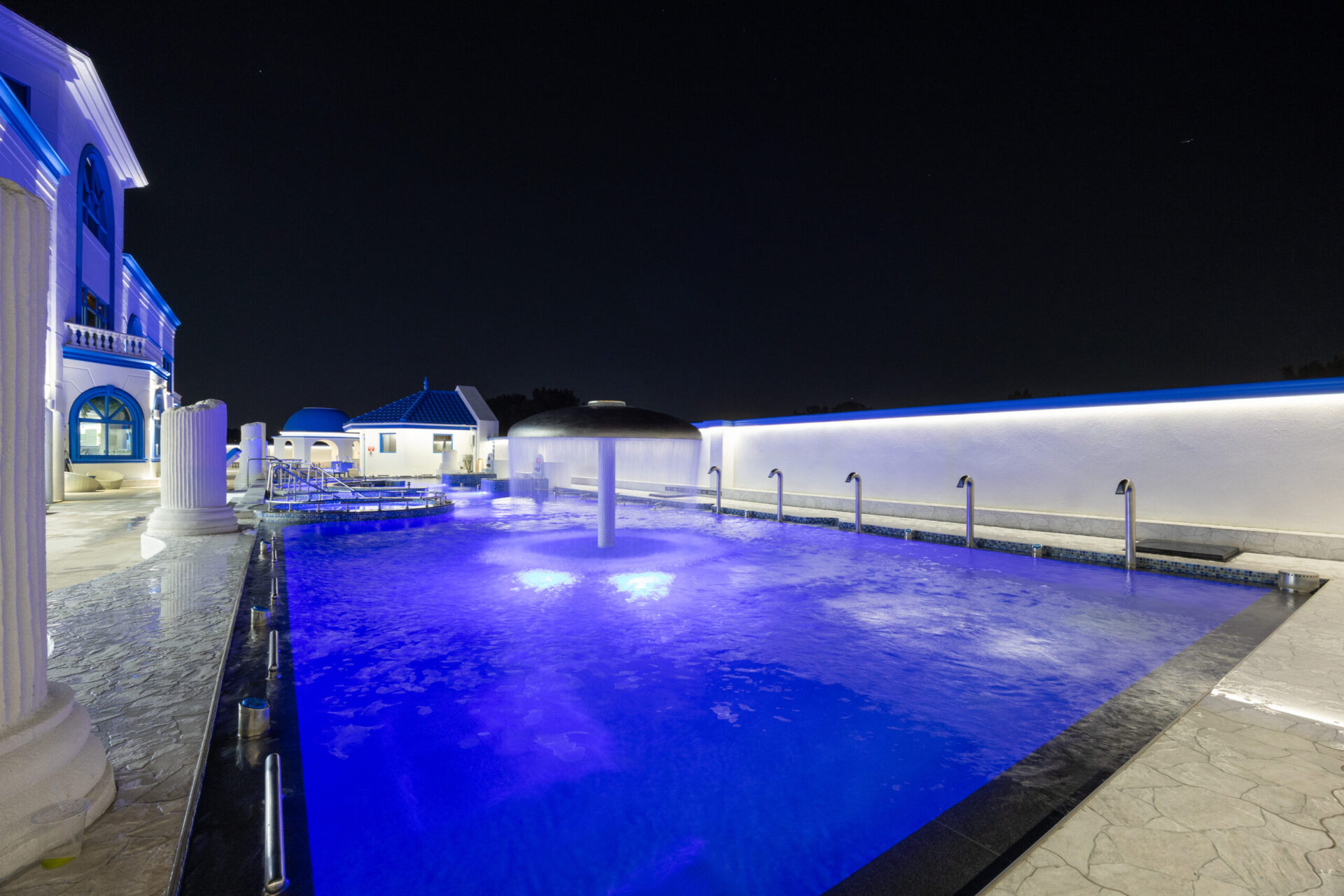Nighttime view of the mushroom jet and standing medi pools. Showcasing water cascading from the umbrella shaped mushroom jet.