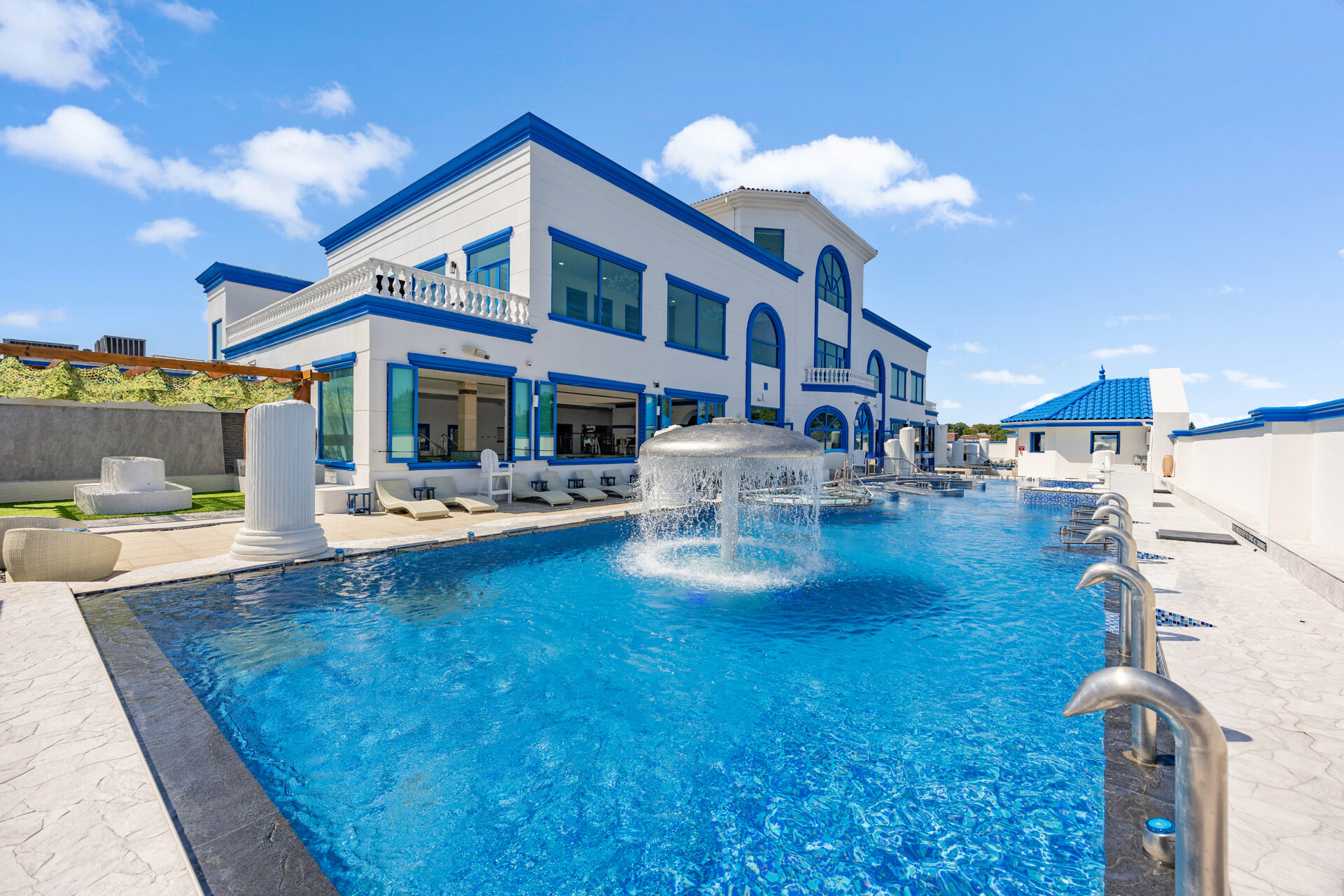 Wide angle of Spa Castle outdoor pool area, featuring the standing medi pool, waterfall and lounge chairs.