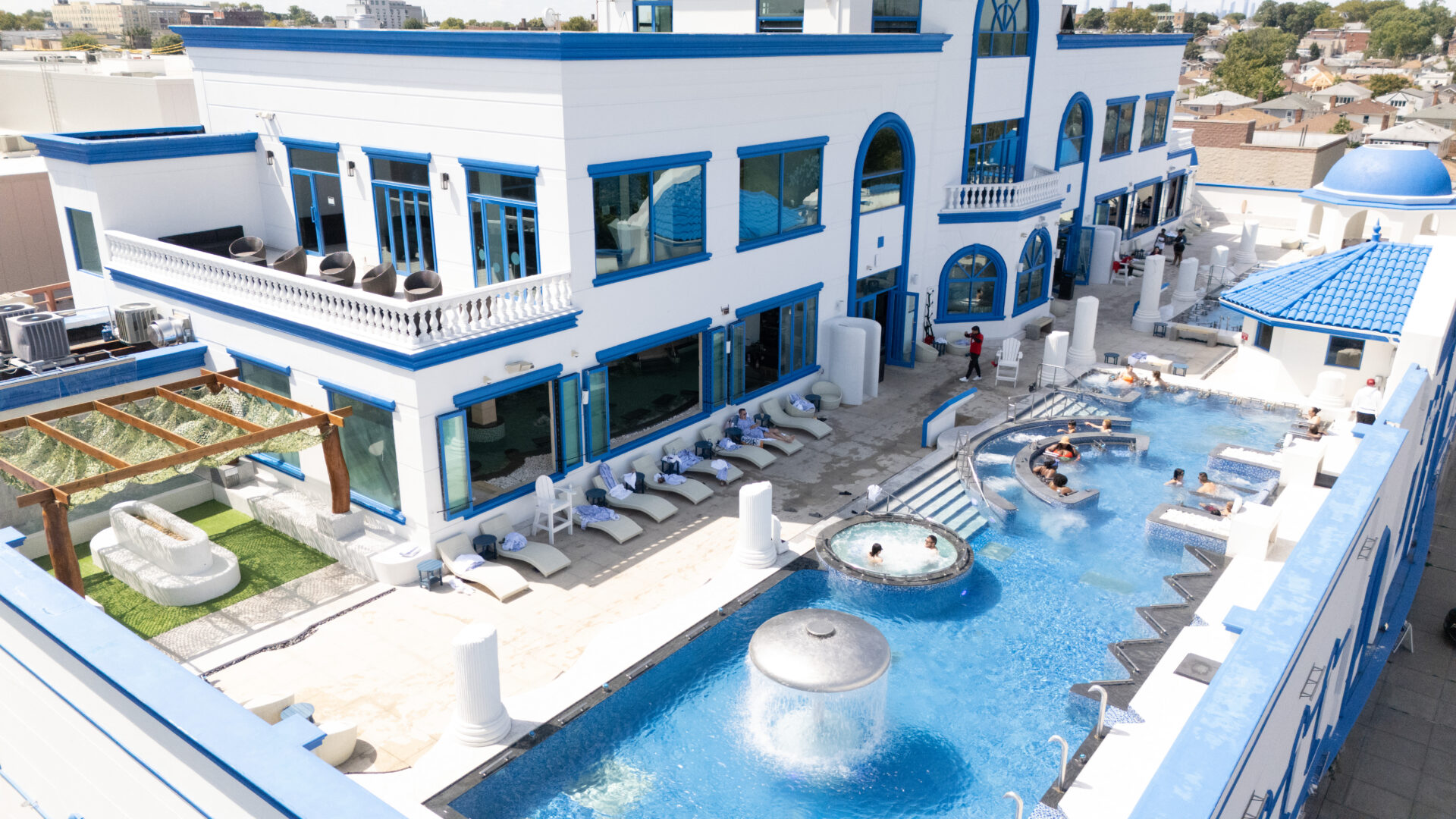 A birds-eye view of spa castle's outdoor pools. Focusing on the standing medi pool and waterfall, featuring guests enjoying the pool.