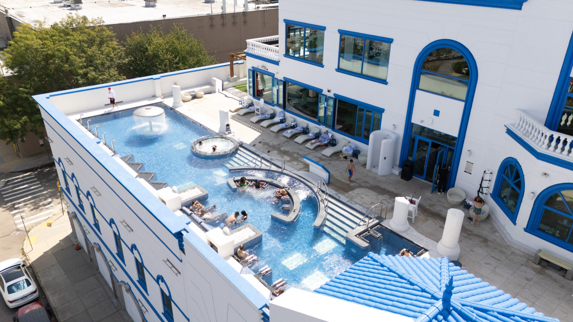 A birds-eye view of spa castle's outdoor pools. Focusing on the standing medi pool, featuring ten guests enjoying the pool.