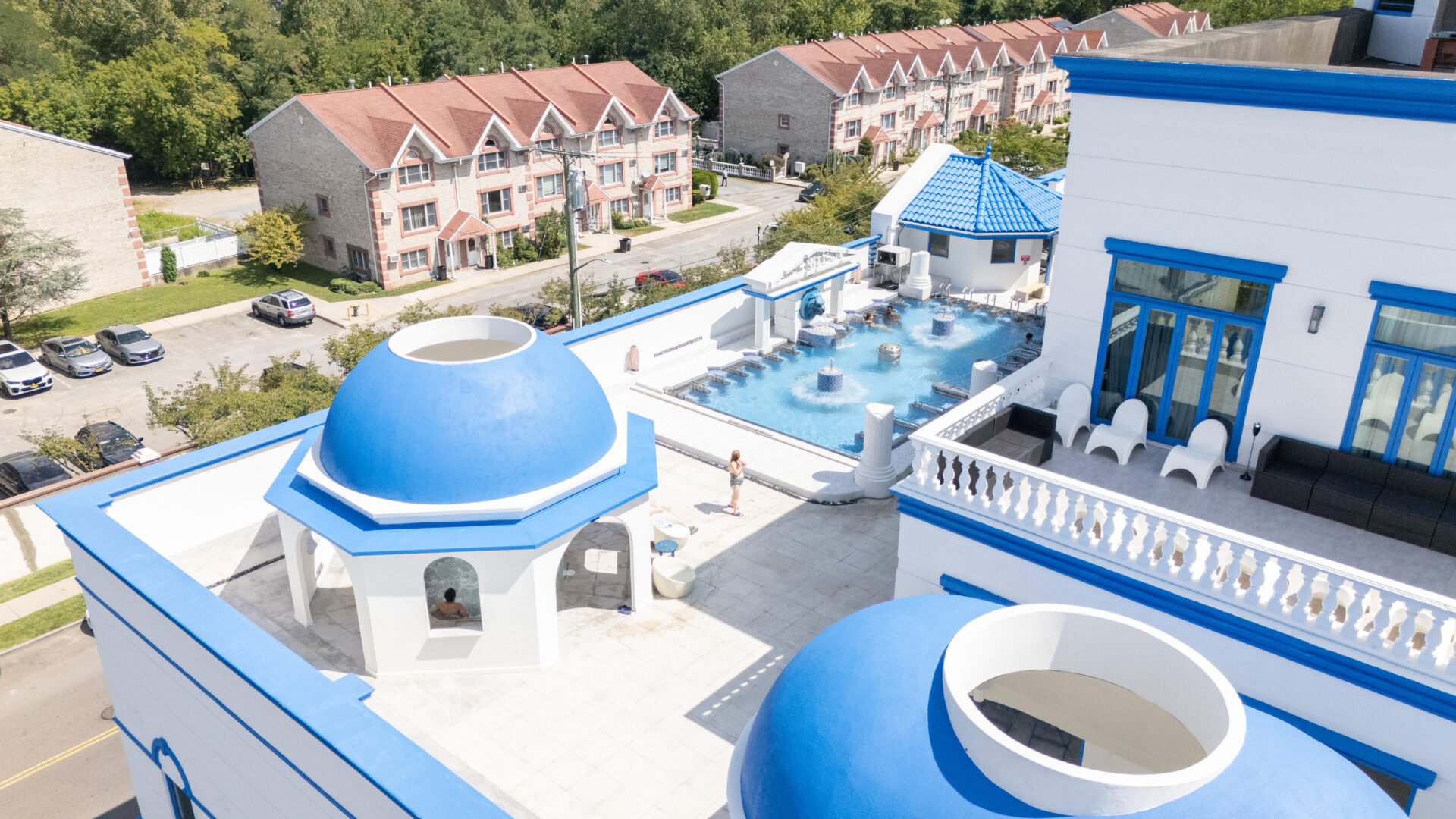 A birds-eye view of spa castle's outdoor pools. Focusing on the Grotto hot tub, featuring a guest enjoying the pool.